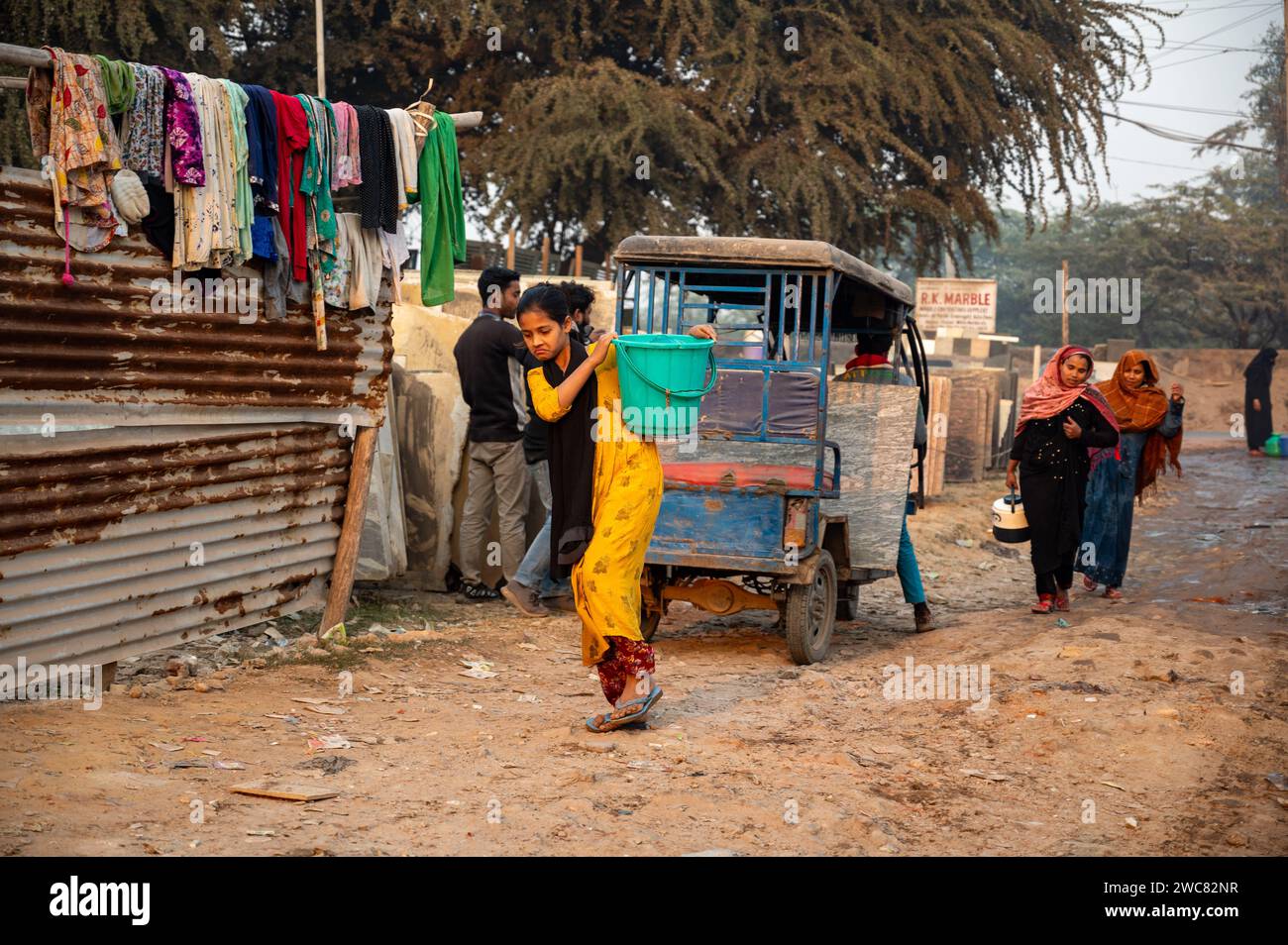 Neu-Delhi, Indien. Januar 2024. Rohingya Flüchtlingsmädchen geht nach Hause und bringt Trinkwasser in Plastikbehältern, die von einem Verteilungspunkt im Flüchtlingslager Madanpur Khadar Rohingya geholt wurden. 1.100 Rohingyas, die in den Lagern von Madanpur Khadar leben, sind von der kommunalen Wasserversorgung abhängig. (Foto: Pradeep Gaur/SOPA Images/SIPA USA) Credit: SIPA USA/Alamy Live News Stockfoto