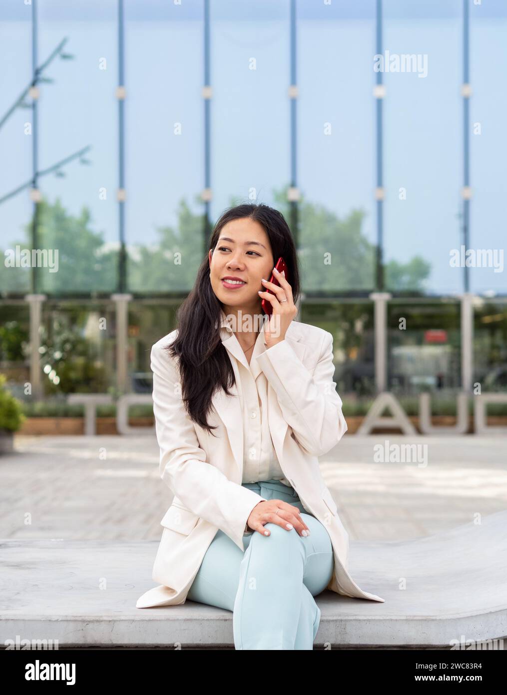 Asiatische Geschäftsfrau, die in einem Finanzviertel per Smartphone spricht Stockfoto
