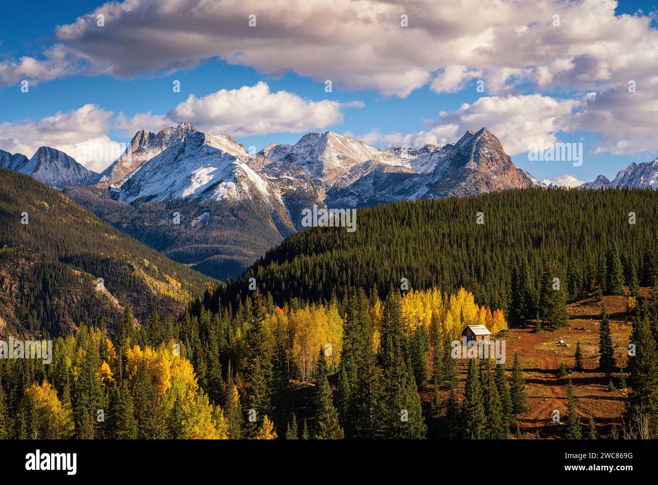 Bergbauhütte, eingebettet in Aspen- und Kiefernwälder unter schneebedeckten Bergen entlang des Million Dollar Highway in Colorado Stockfoto