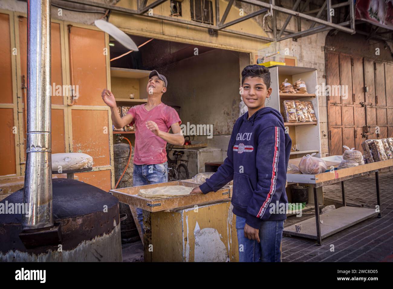 Die palästinensischen Jungs machen Brot in der örtlichen Bäckerei in der Innenstadt von Hebron, Westjordanland, Palästina. Stockfoto