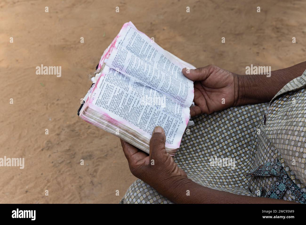 Nahaufnahme Buch, Hände einer alten afrikanerin, die die Bibel im Hof liest, Dorf in Botswana Stockfoto