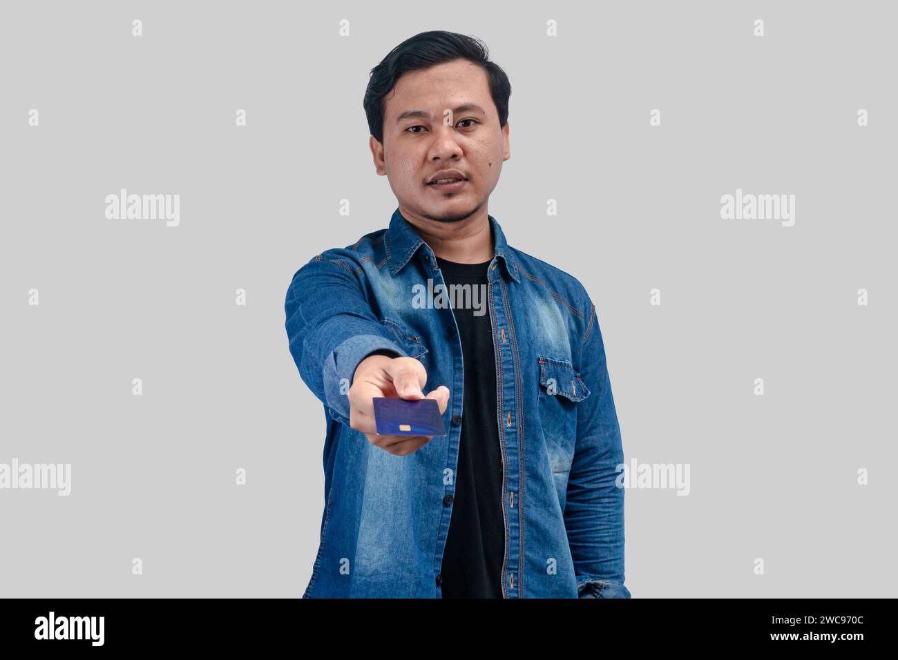 Ein junger asiatischer Mann zeigt seine Kreditkarte auf einem isolierten Hintergrund Stockfoto