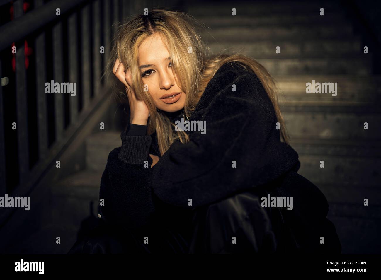 Eine weiße attraktive Frau in schwarzer Grunge-Kleidung posiert auf der Treppe Stockfoto