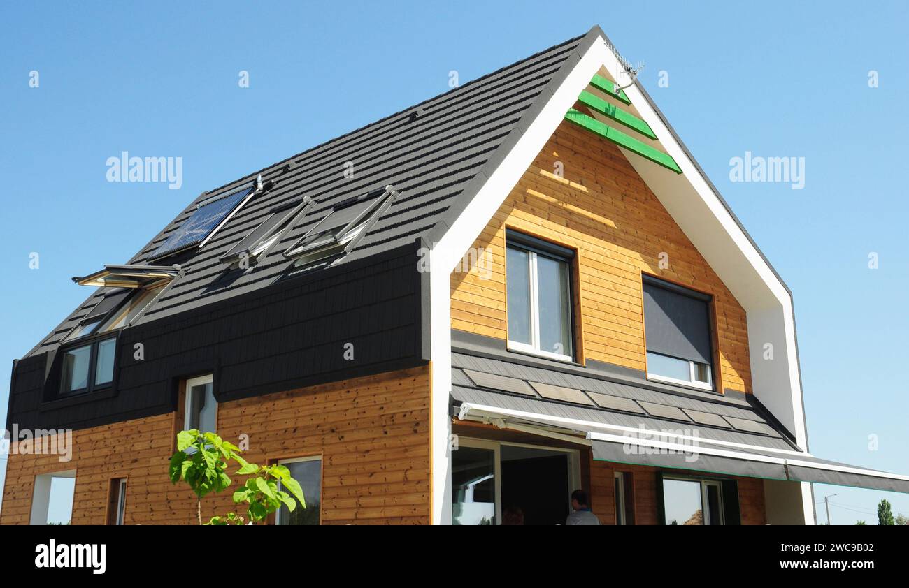 Modernes Holzhaus mit Markise über der Wohnterrasse zum Sonnenschutz. Transparente Vorhänge, Sonnenschirme, Jalousien, Vorhänge für Energieeffizienz. Stockfoto