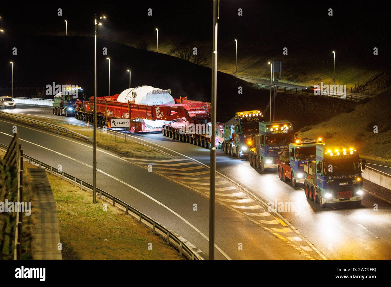 Hirwaun Power, Drax, transportierte ein 700 Tonnen schweres Lastkraftfahrzeug zusammen mit einer Polizeieskorte auf der A456 in der Nähe von Llanelli Hill als Teil der Arbeiten zum Bau eines neuen Gaskraftwerks, des Kraftwerks, das einmal in Betrieb war, kann bis zu 1.500 Stunden in einem beliebigen Jahr laufen. Sie wird als Reserve für andere Stromquellen dienen, darunter wetterabhängige Windturbinen und Solarparks, Llanelli Hill, Vereinigtes Königreich, 15. Januar 2024 Link to Hirwaun Power; https://www.drax.com/about-us/our-projects/hirwaun-power/#frequently-asked-questions-faqs (Foto: Thomas Winstone/News Images) in Llan Stockfoto