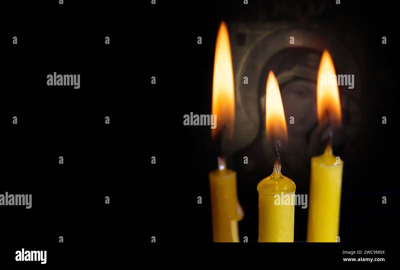 Kerzen auf schwarzem Hintergrund mit einer Religionsfigur aus der Nähe Stockfoto