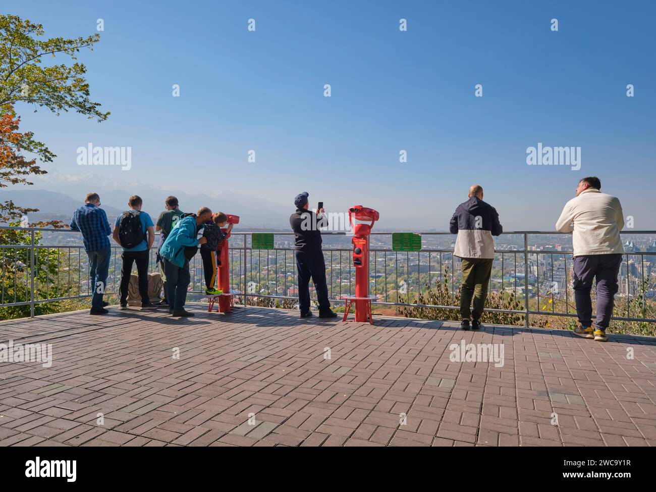 Touristen, die einen Aussichtspunkt genießen, die Skyline betrachten und ein Fernglas benutzen. Auf dem Gipfel des touristischen Vergnügungsparks von Kok Tobe in Almaty, K Stockfoto