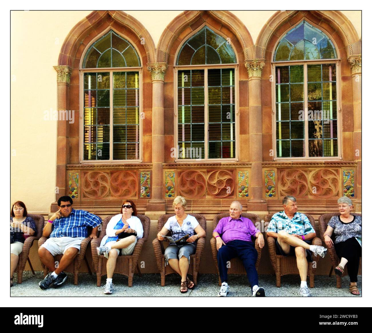 Männer und Frauen sitzen in einer Reihe von Stühlen vor dem Ringling Museum in Sarasota, FL. Stockfoto