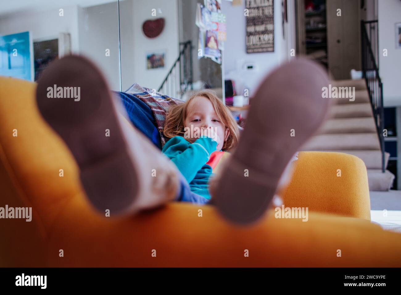 Vorschuler sitzt im Stuhl mit Schuhen auf falschen Füßen Stockfoto