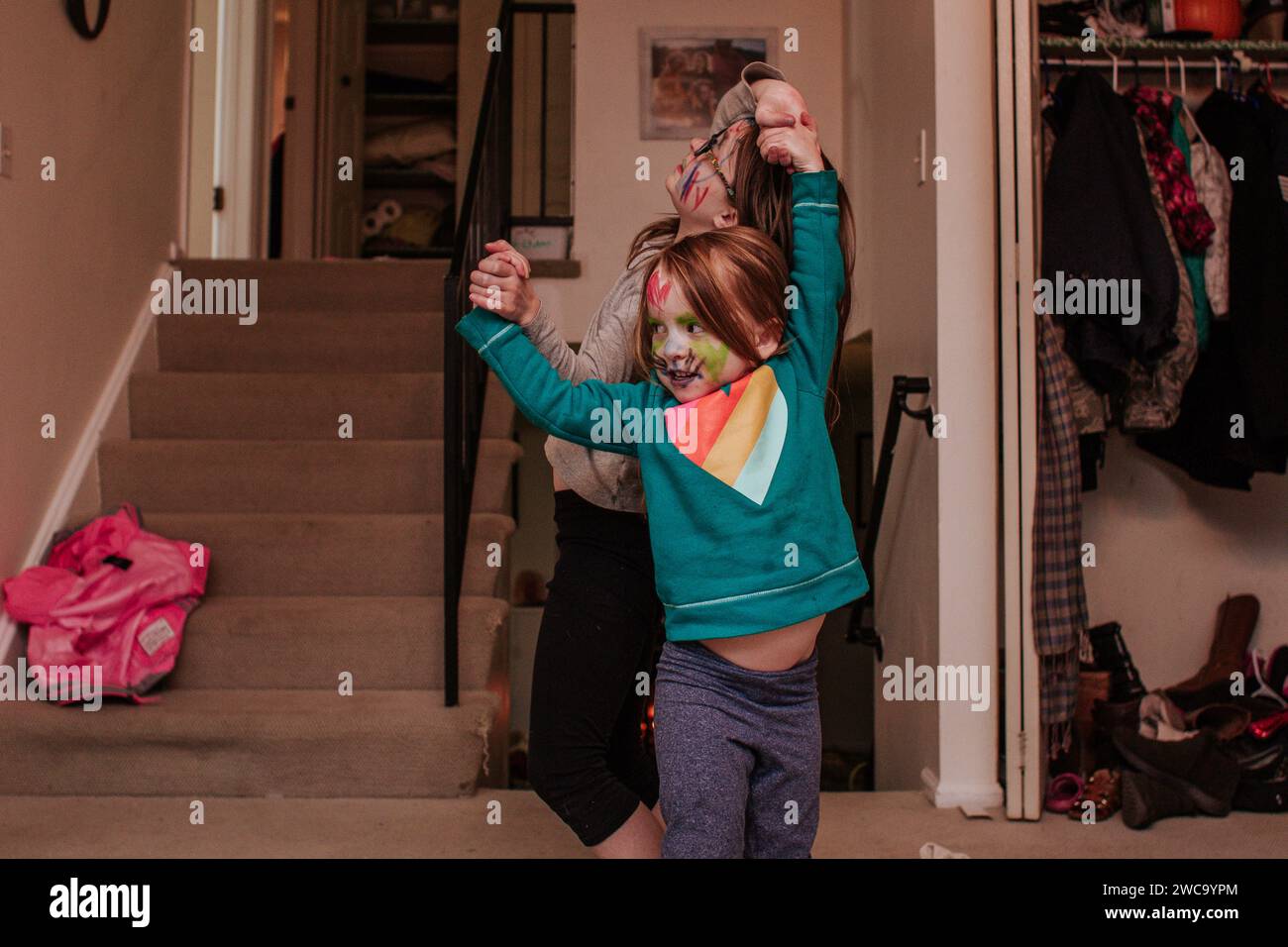 Dumme Geschwister tanzen im Wohnzimmer mit Markierungen auf Gesichtern Stockfoto