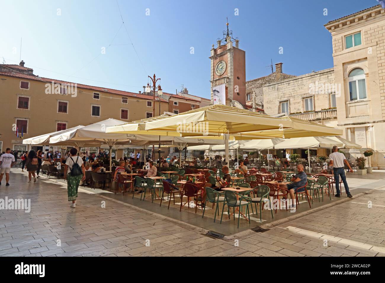 Leute sitzen an Tischen auf dem Volksplatz, Zadar, Kroatien Stockfoto