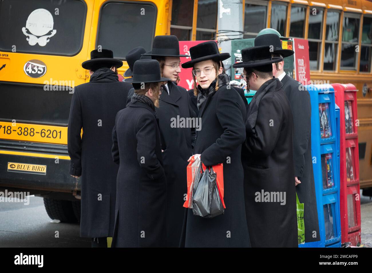 Eine Gruppe orthodoxer jüdischer Studenten wartet auf einen Bus, der sie zu einem anderen Teil von Brooklyn bringt, um Talmud zu studieren. Auf der Bedford Avenue in Brooklyn. Stockfoto