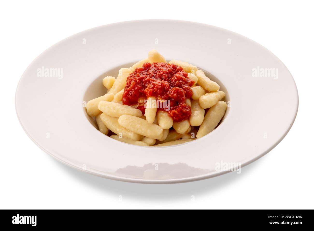 Gnocchi mit Tomatensauce in weißer Platte isoliert auf weiß mit Schnittpfad enthalten. Typische Gnocchi aus den italienischen Alpen. Gnocchi aus dem Varait Stockfoto
