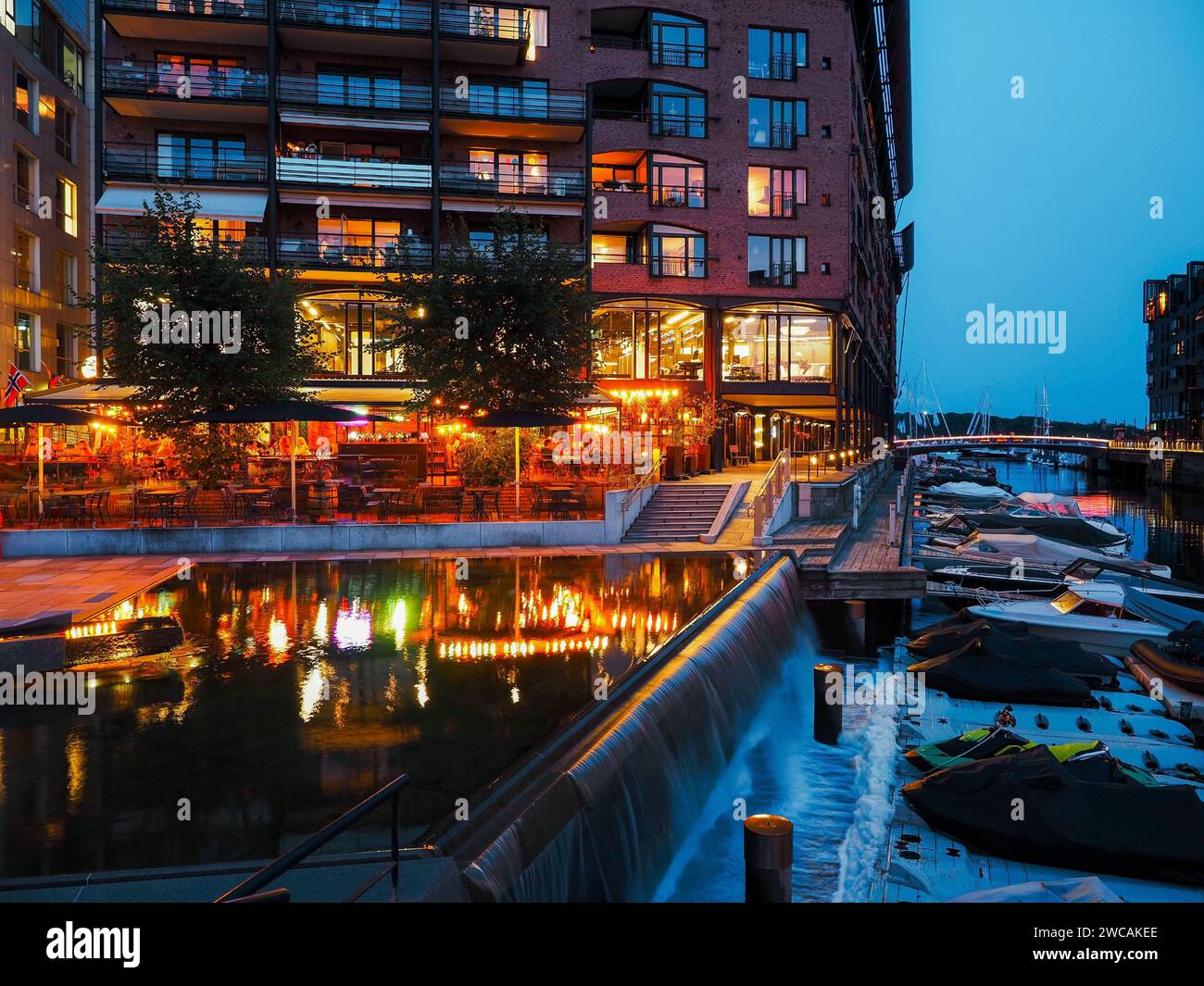 Neue städtische Wohngebäude und Restaurants auf dem Wasser im Dock und vertäute Wasserfahrzeuge in der Nähe, zeitgenössische Architektur in Oslo-Stadt, Norwegen Stockfoto