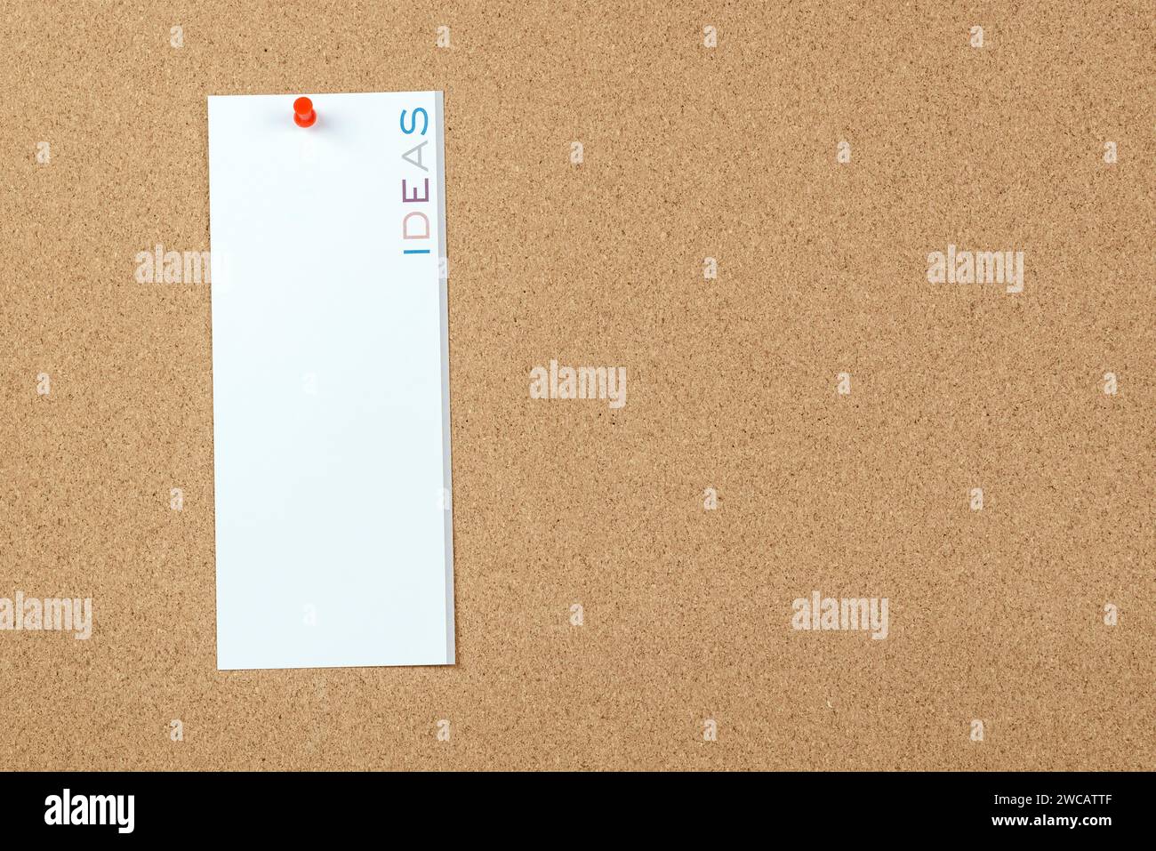 Leere Notiz mit dem Wort „Ideen“, das vertikal auf einem Korkbrett gedruckt ist. Kopierbereich. Stockfoto