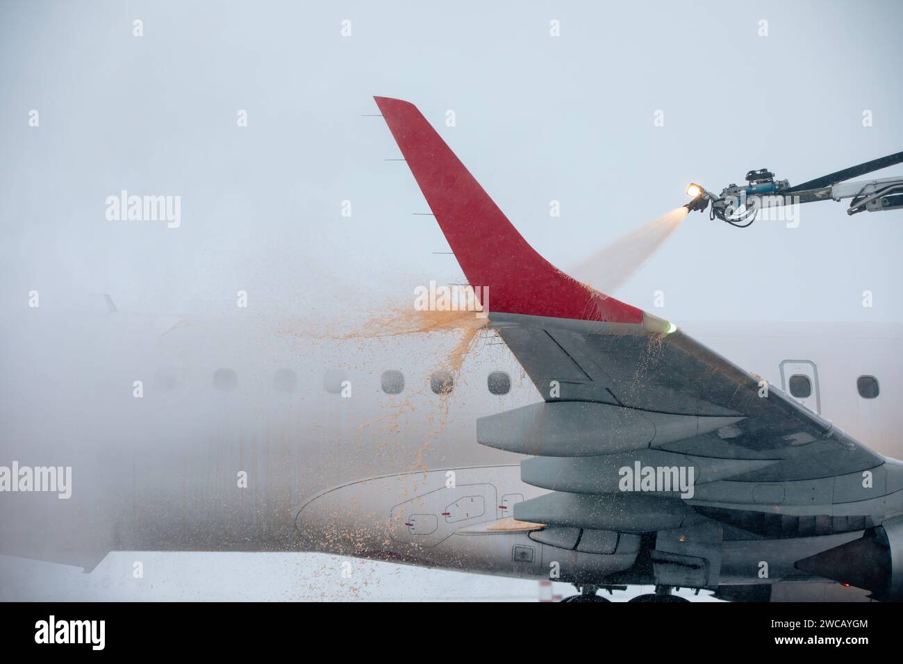 Enteisung des Flugzeugflügels vor dem Flug. Winter frostiger Tag und Bodenservice am Flughafen bei Schneefall. Stockfoto