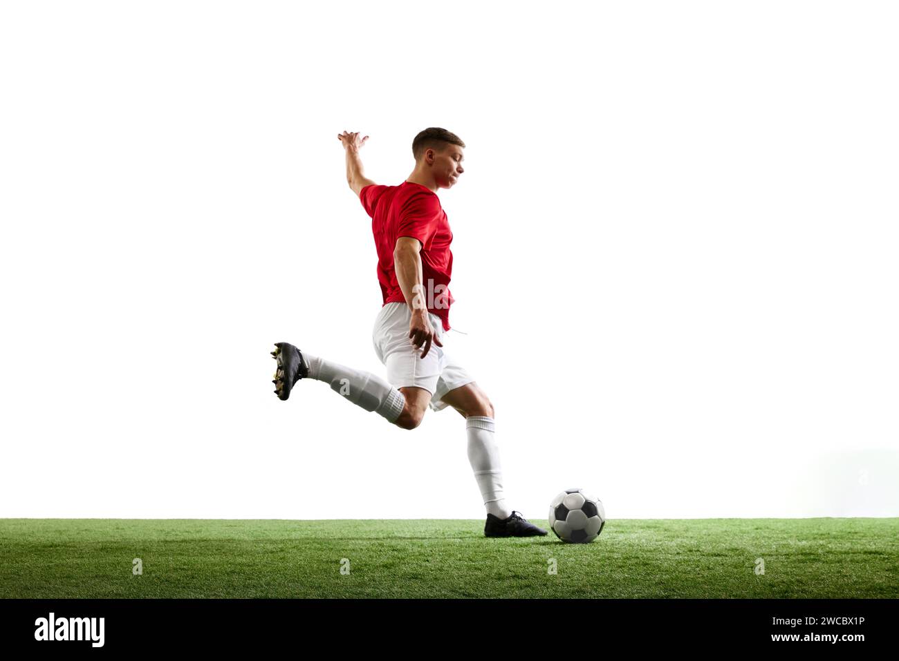 Triumphierender Treffer zum Sieg. Der professionelle Fußballspieler schickt den Ball vor weißem Hintergrund ins Tor. Stockfoto