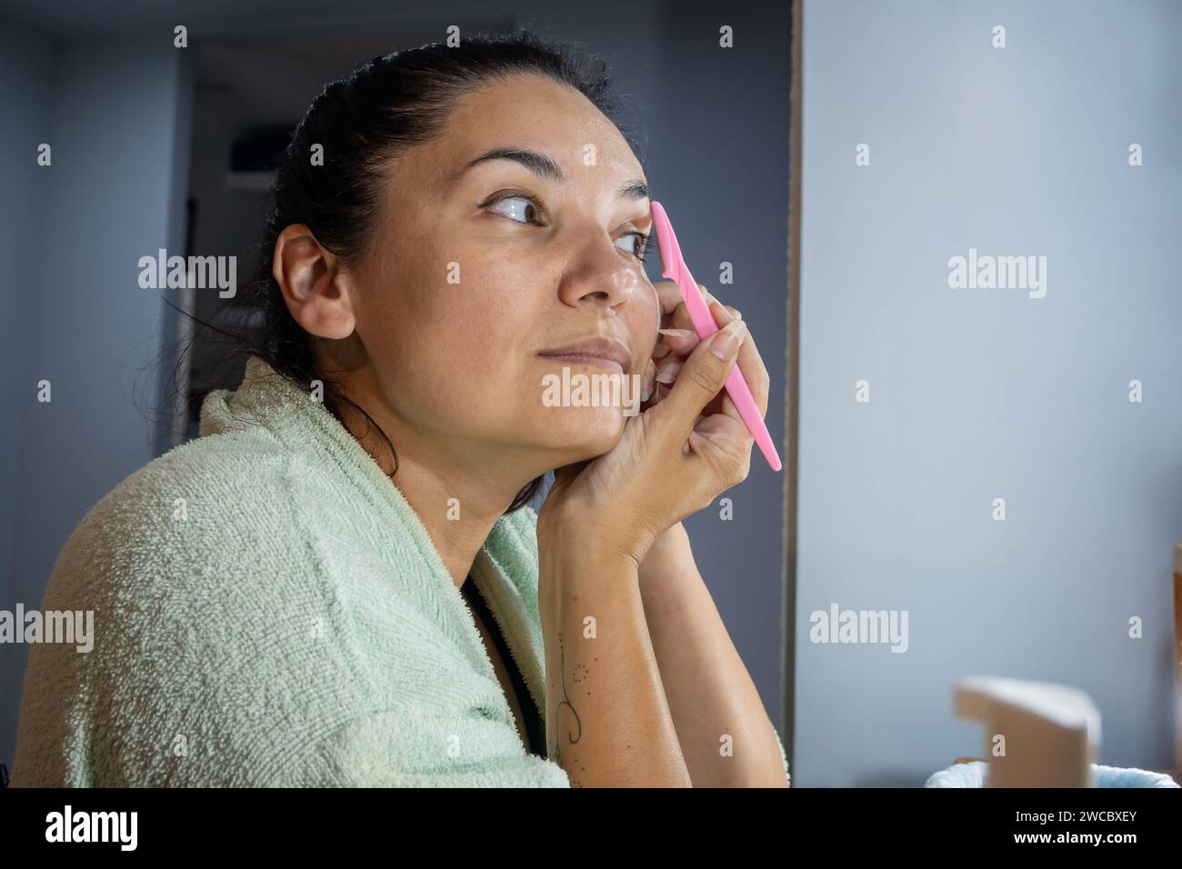 Latina-Frau benutzt Augenbrauen Einweg-Shaper vor ihrem Frisiertisch im Schlafzimmer. Stockfoto