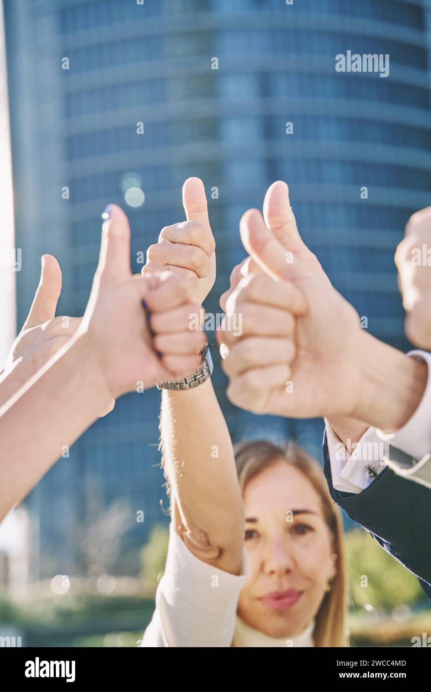 Gruppe von Geschäftsleuten mit erhobenen Händen und Daumen nach oben. Vertikales Foto, selektiver Fokus auf den Händen, reife Frau unscharf. Leichennahmebildung Stockfoto