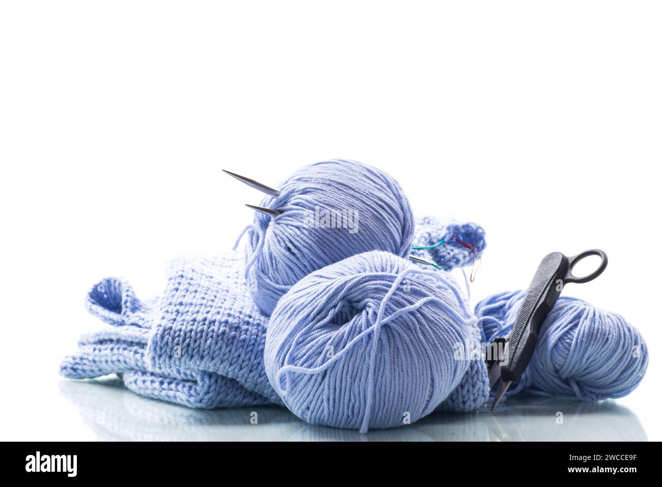 Set für Handstricken, blaues Garn, Stricknadeln und mehr isoliert auf weißem Hintergrund. Stockfoto