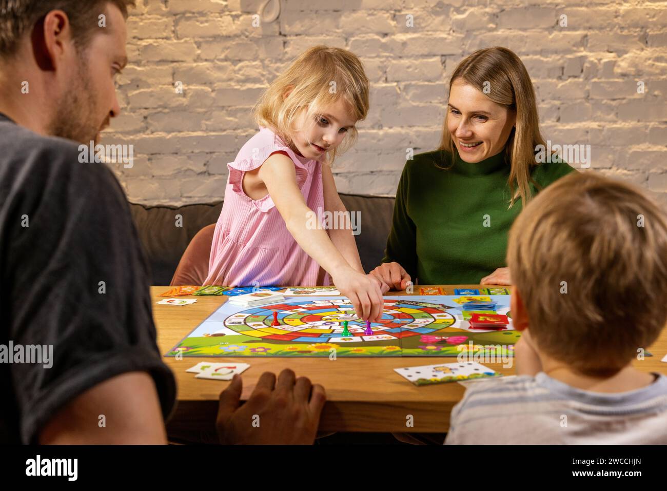 Familie mit zwei Kindern, die Zeit zusammen verbringen und Brettspiele spielen, während sie zu Hause am Tisch sitzen. Familienzeit Stockfoto