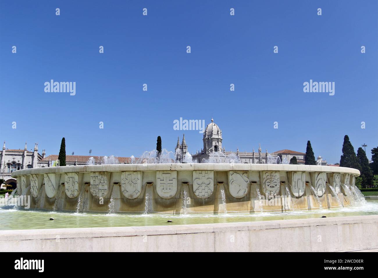 Hinter dem Brunnen im Jardim da Praca do Império, einem Garten in Lissabon. Das Kloster Jerónimos oder Hieronymitenkloster ist ein ehemaliges Kloster des Ordens des Heiligen Jerome in der Nähe des Flusses Tejo in der Pfarrei Belém in der portugiesischen Gemeinde Lissabon. Sie wurde im 16. Jahrhundert zur Nekropole der portugiesischen Königsdynastie Aviz, wurde aber am 28. Dezember 1833 durch einen staatlichen Erlass säkularisiert und das Eigentum an die gemeinnützige Institution Real Casa Pia de Lisboa übertragen. Stockfoto