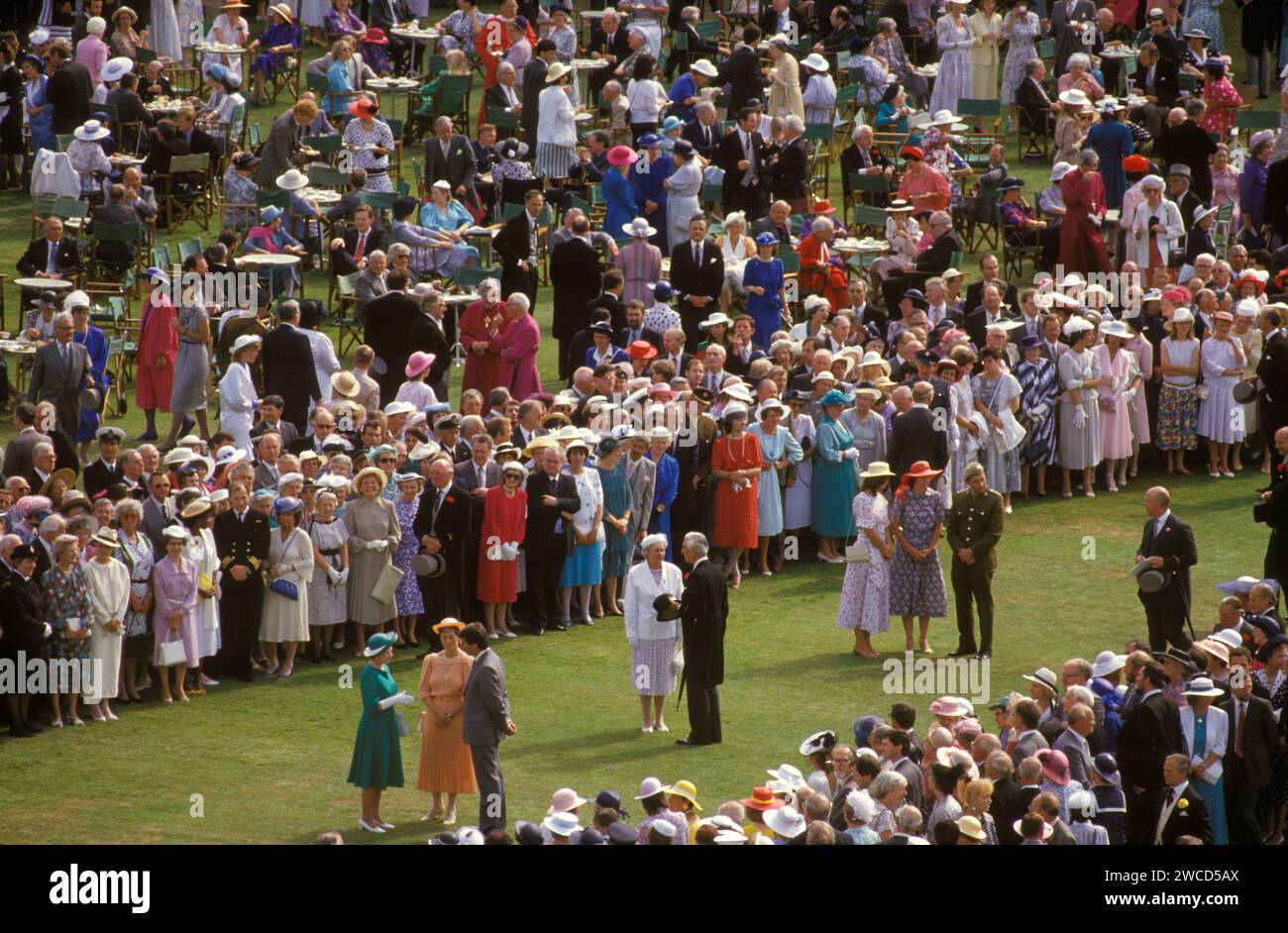Queen Elizabeth II. Buckingham Palace Gartenparty. Die Königin in grünem Kleid (unten links) und mit weißen langen Handschuhen, trifft Leute, die nominiert wurden, um sie zu treffen und an einer ihrer Sommergartenpartys teilzunehmen. London, England Juni 1985. HOMER SYKES AUS DEN 1980ER JAHREN Stockfoto