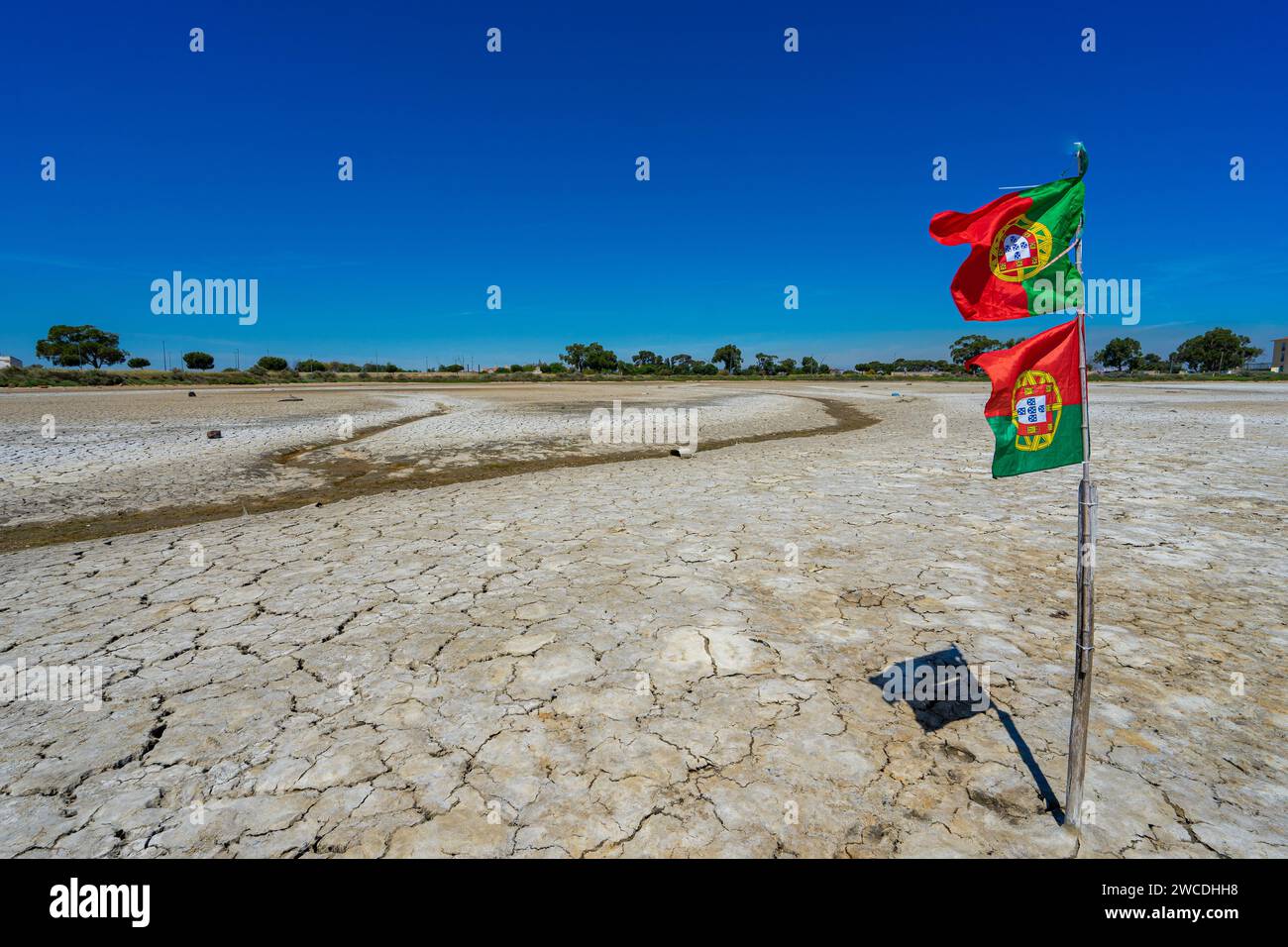 Trockener und gerissener Boden des trockenen Flusses mit portugiesischer Nationalflagge Stockfoto