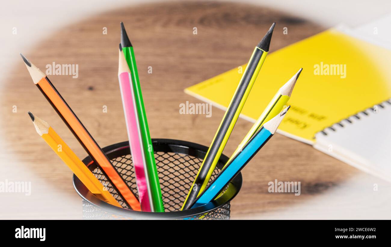 Erhellen Sie Ihren Arbeitsplatz mit diesem einladenden Bild mit farbenfrohen Bleistiften und einem leeren Notizblock, der auf einem aufgeräumten Schreibtisch platziert ist Stockfoto