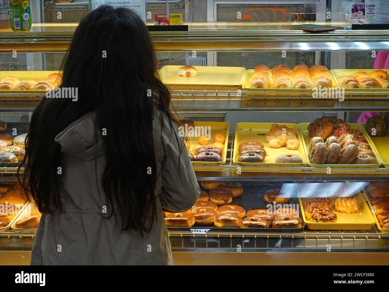 Ein kleines Mädchen, das einen Donut für einen morgendlichen Snack auswählt - November 2023 Stockfoto