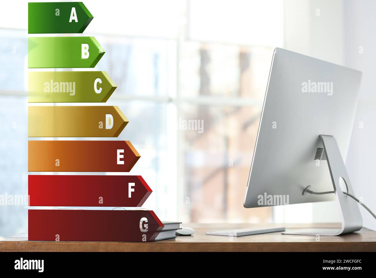 Energieeffizienzbewertung am Arbeitsplatz. Holztisch mit Computermonitor im Innenbereich Stockfoto