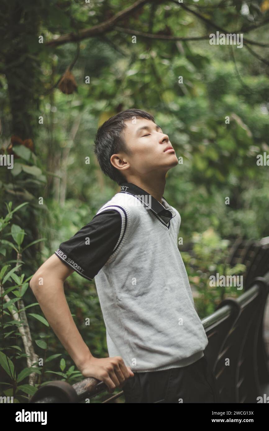 Männlicher Teenager, der sich gegen den Zaun lehnt, in Selbstreflexion-Pose Stockfoto