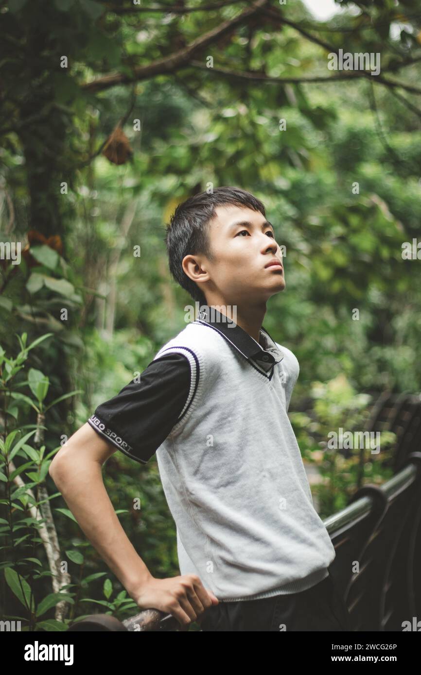 Männlicher Teenager, der sich gegen den Zaun lehnt, in einer Selbstreflexion-Pose Stockfoto