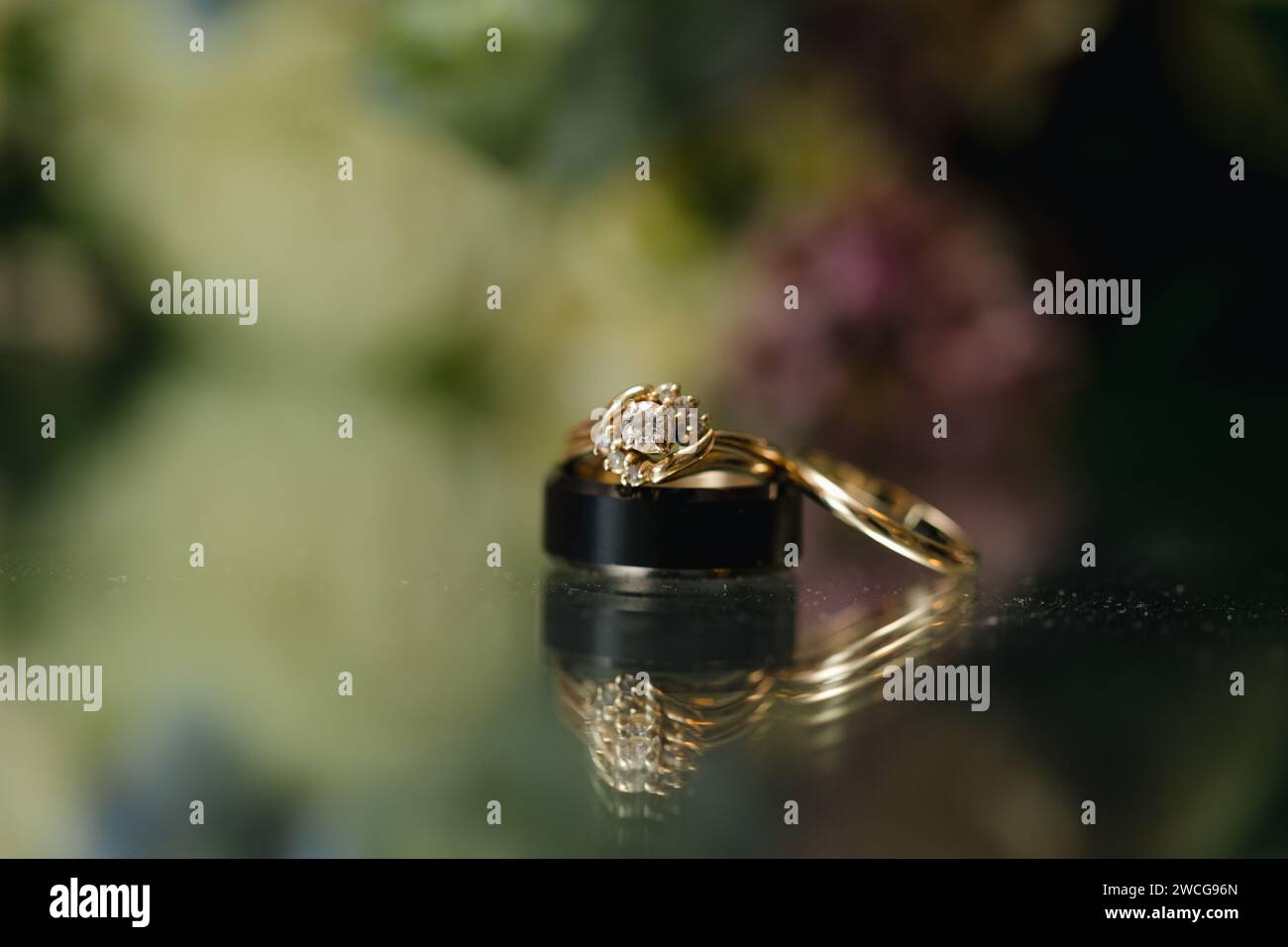 Goldener Ehering auf floralem Hintergrund, Hochzeitshintergrund Stockfoto