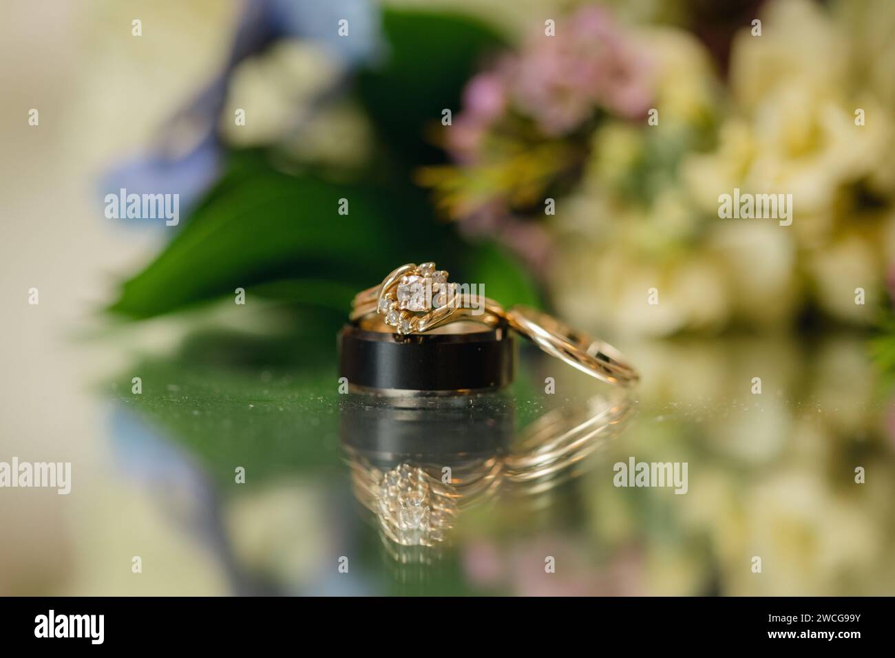 Goldener Ehering auf floralem Hintergrund, Hochzeitshintergrund Stockfoto