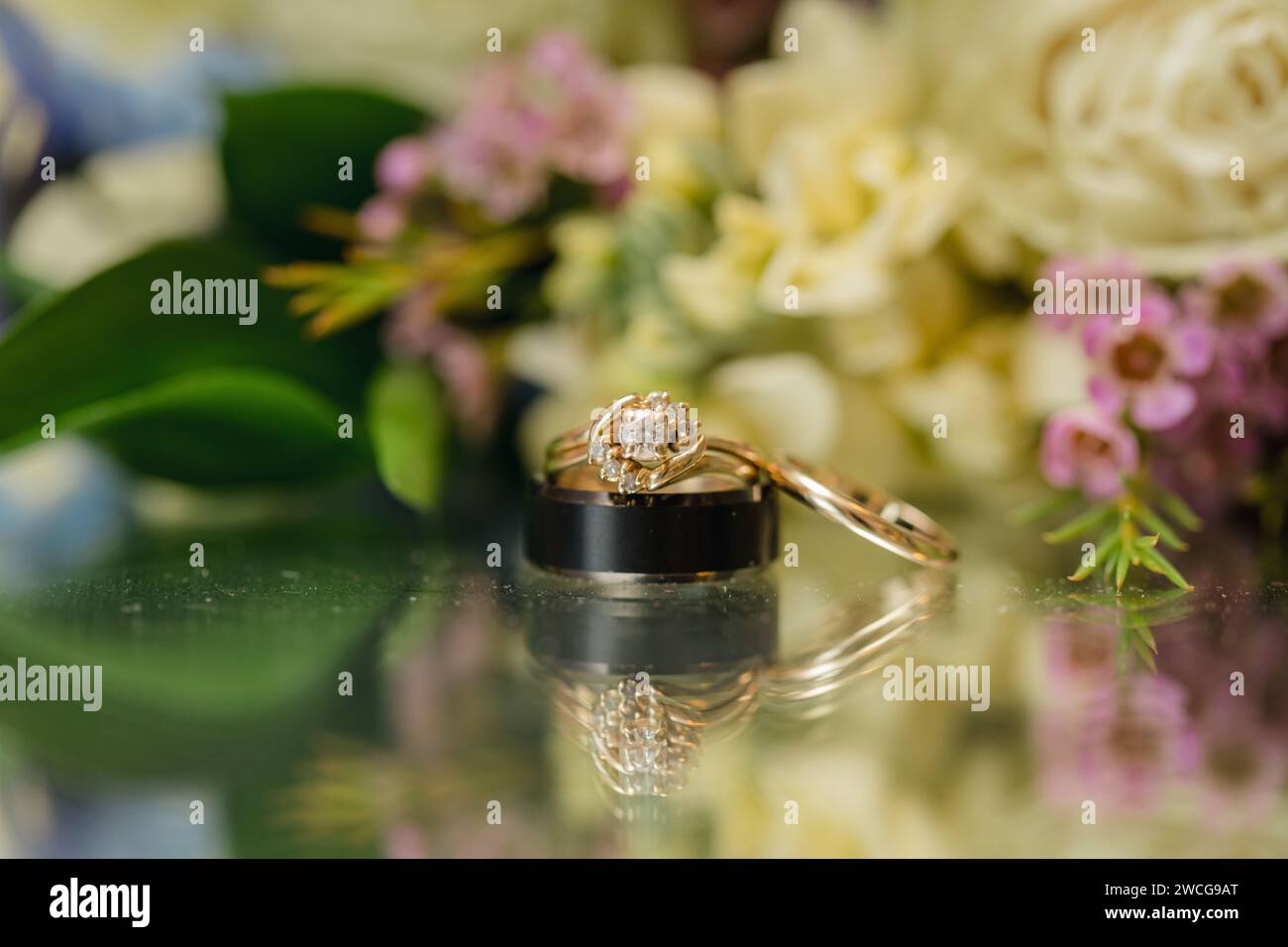 Goldener Ehering auf floralem Hintergrund, Hochzeitshintergrund Stockfoto