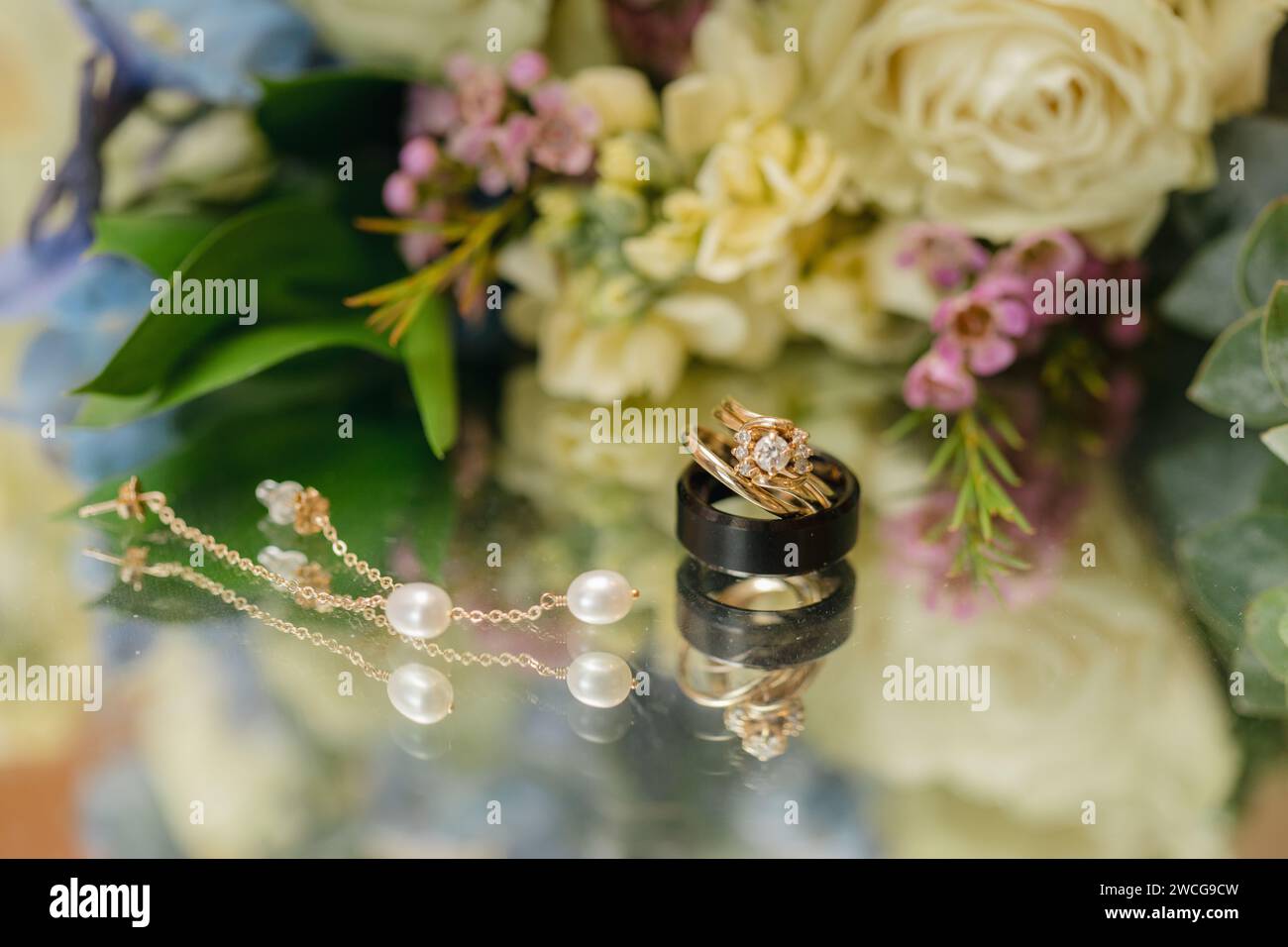 Goldener Ehering auf floralem Hintergrund, Hochzeitshintergrund Stockfoto