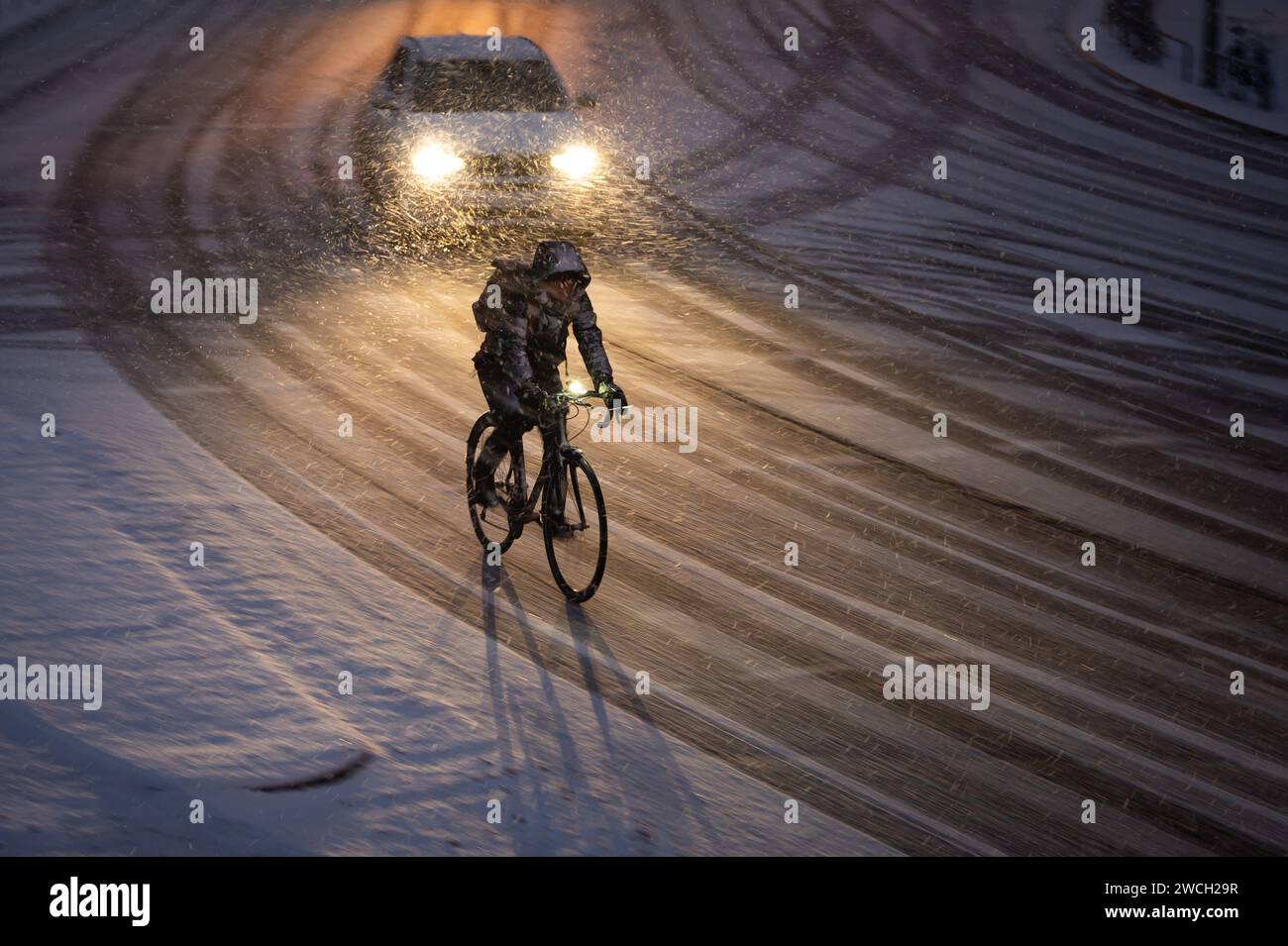 Hamburg, Deutschland. Januar 2024. Ein Radfahrer fährt am Morgen auf einer schneebedeckten Straße. Der Winter ist wieder in Deutschland. Neuschnee und vereiste Straßen haben zu mehreren Unfällen geführt. Die Unbedenklichkeit für vereiste Straßen ist vorerst nicht in Sicht. Quelle: Jonas Walzberg/dpa/Alamy Live News Stockfoto
