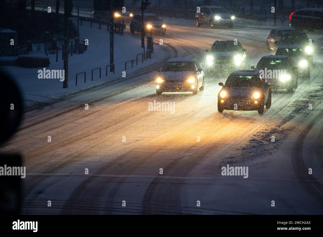 Hamburg, Deutschland. Januar 2024. Autos fahren morgens auf einer schneebedeckten Straße. Der Winter ist wieder in Deutschland. Neuschnee und vereiste Straßen haben zu mehreren Unfällen geführt. Die Unbedenklichkeit für vereiste Straßen ist vorerst nicht in Sicht. Quelle: Jonas Walzberg/dpa/Alamy Live News Stockfoto