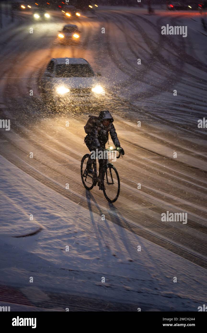Hamburg, Deutschland. Januar 2024. Ein Radfahrer fährt am Morgen auf einer schneebedeckten Straße. Der Winter ist wieder in Deutschland. Neuschnee und vereiste Straßen haben zu mehreren Unfällen geführt. Die Unbedenklichkeit für vereiste Straßen ist vorerst nicht in Sicht. Quelle: Jonas Walzberg/dpa/Alamy Live News Stockfoto