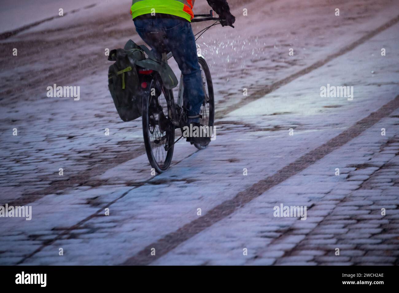 Hamburg, Deutschland. Januar 2024. Ein Radfahrer fährt am Morgen über Schnee und Kopfsteinpflaster. Der Winter ist wieder in Deutschland. Neuschnee und vereiste Straßen haben zu mehreren Unfällen geführt. Das alles klar für eisige Bedingungen ist vorerst nicht in Sicht. Quelle: Jonas Walzberg/dpa/Alamy Live News Stockfoto