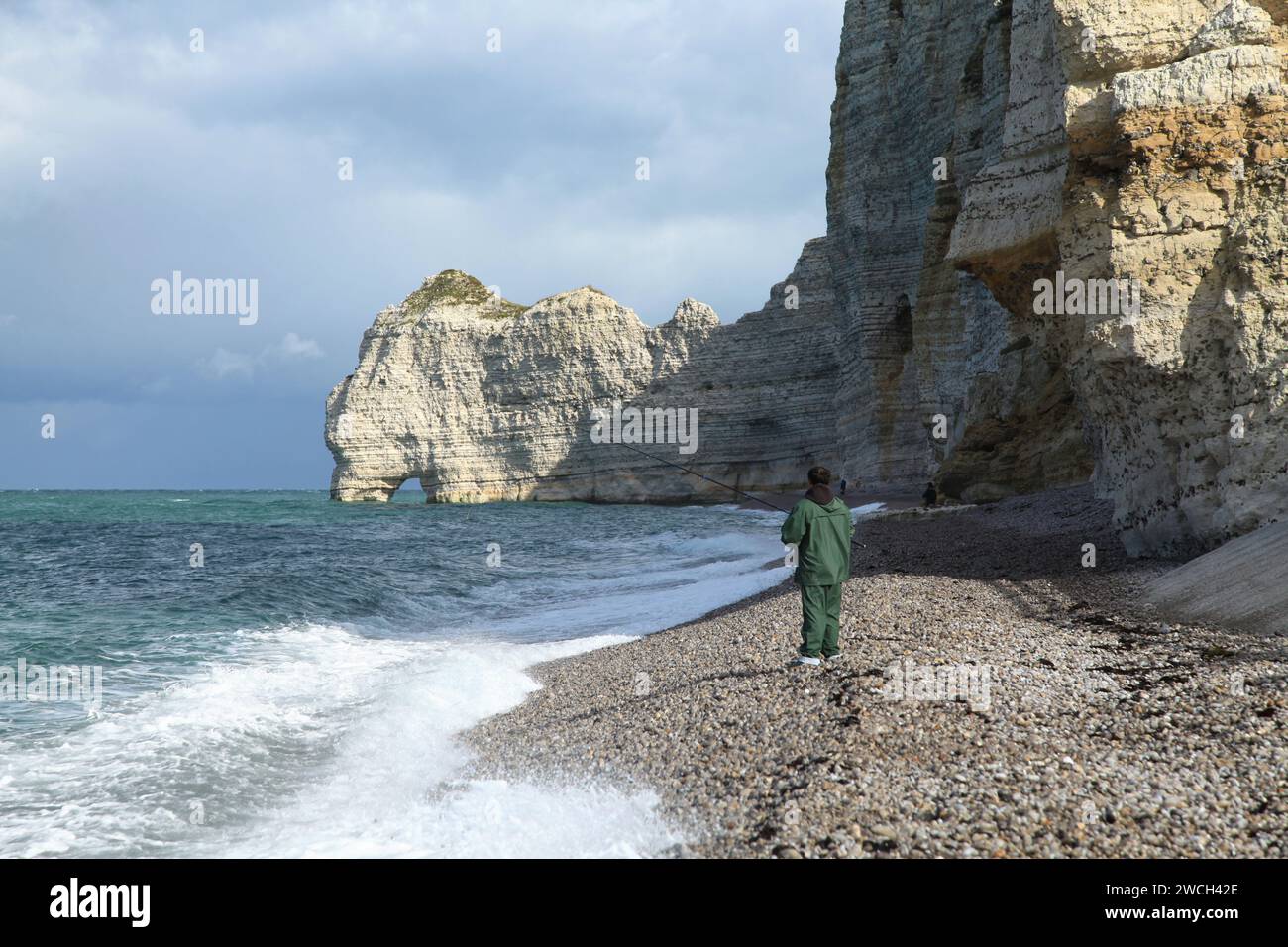 Etretat, Frankreich - 15. Oktober 2012: Angler am Strand werfen seine Leine, um einen Fisch vor der 'Falaise Amont' zu fangen. Stockfoto