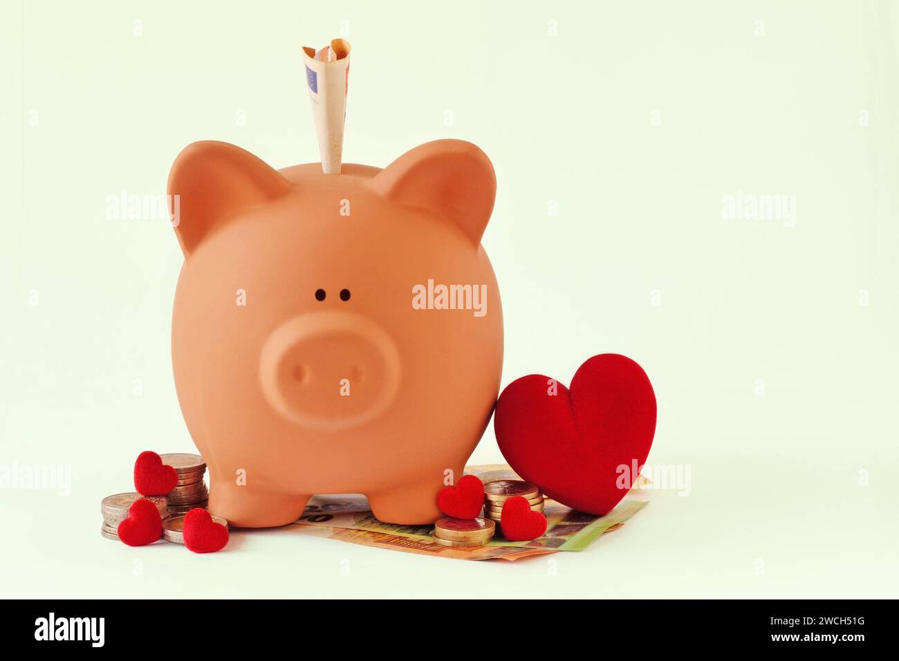 Schweinebank mit Herzen und Geld auf weißem Hintergrund - Konzept von Sparen, Liebe und Spende Stockfoto