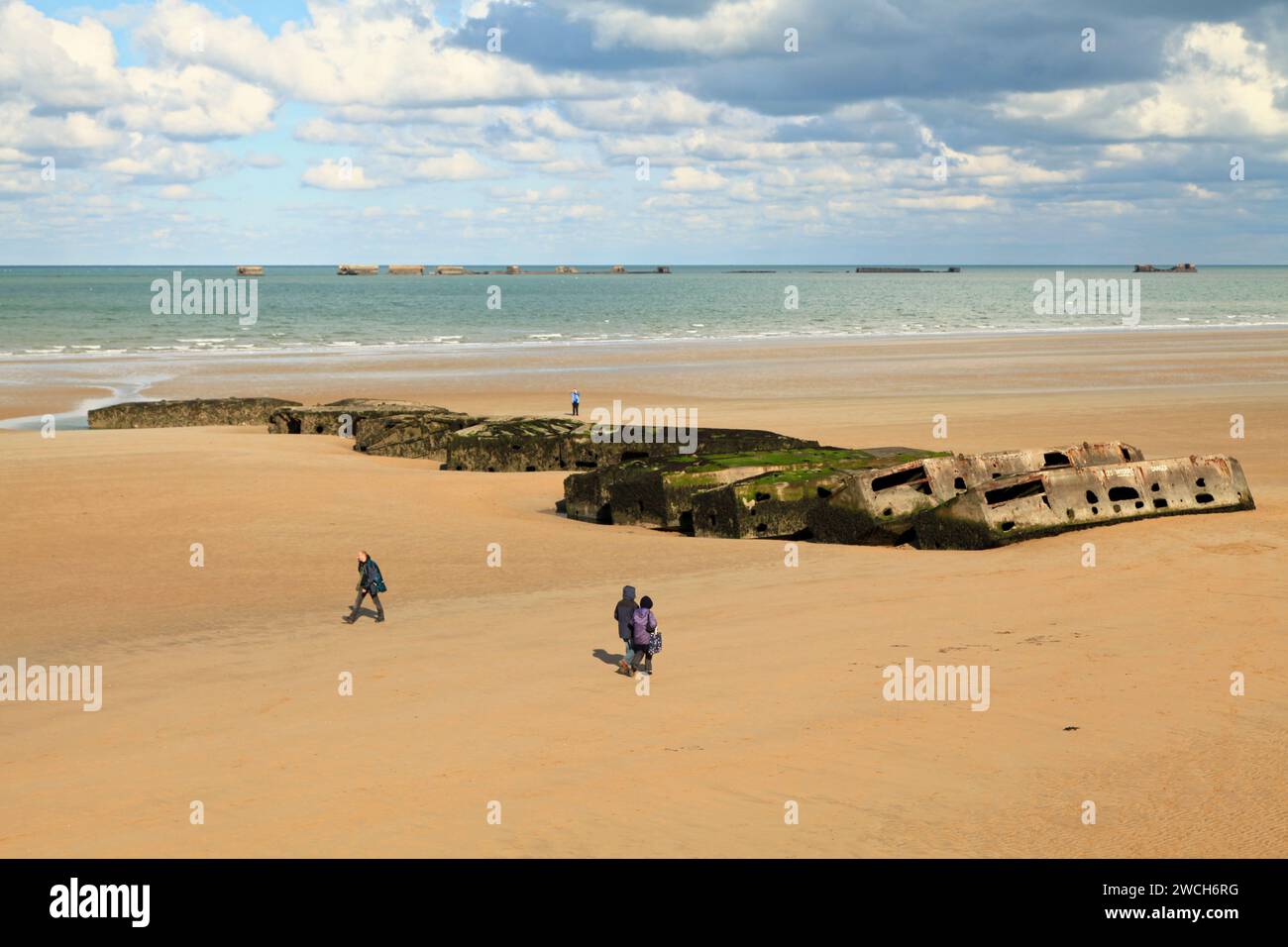 Arromanches-les-Bains, Frankreich - 14. Oktober 2012: Menschen gehen an den Überresten des Maulbeerhafens vorbei. Die Mulberry harbours waren temporär tragbare harb Stockfoto