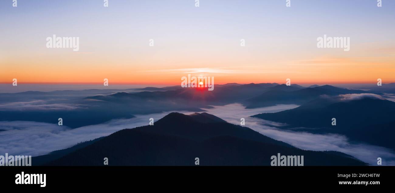 Wunderschöne Panoramalandschaft mit nebligen Bergen bei Sonnenaufgang. Stockfoto