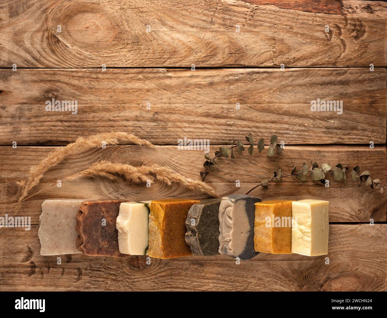 Verschiedene handgefertigte Seifenstangen auf hölzernem Hintergrund. Leerzeichen für Text. Bio-Kosmetikkonzept. Stockfoto