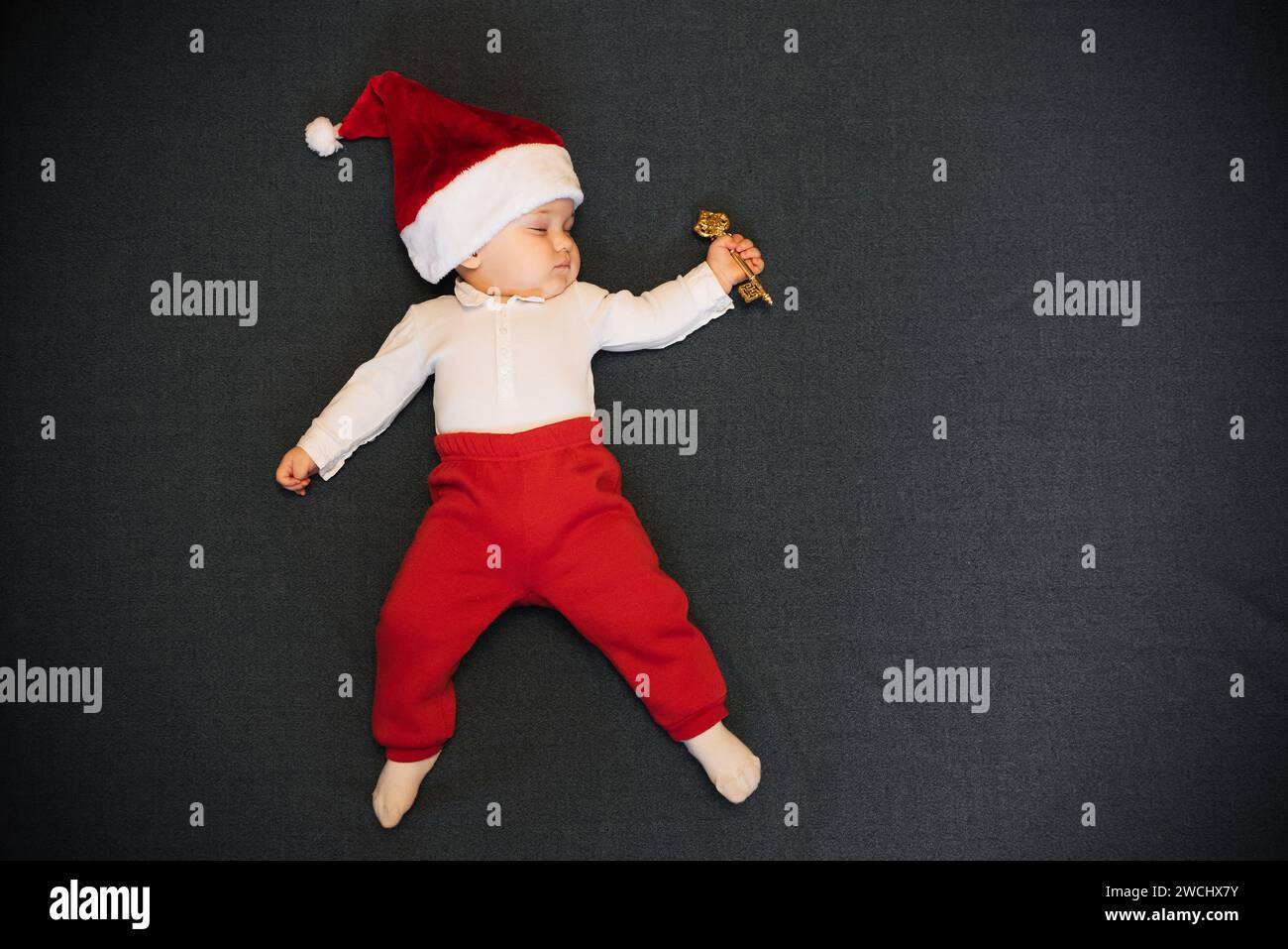 Der schlafende Junge mit dem Hut des Weihnachtsmanns liegt mit einem Schlüssel in der Hand und mit einer Kopie des Raumes Stockfoto