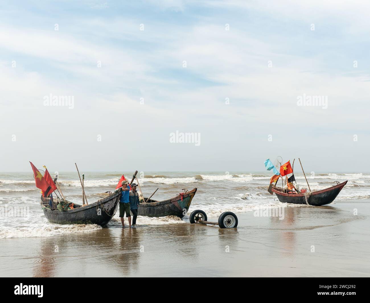 Fischer am Sam Son Beach, Thanh Hoa, Vietnam, mit ihren Booten am Strand am Ende des Arbeitstages. Bereit, sie weiter den Strand hinauf zu schleppen Stockfoto