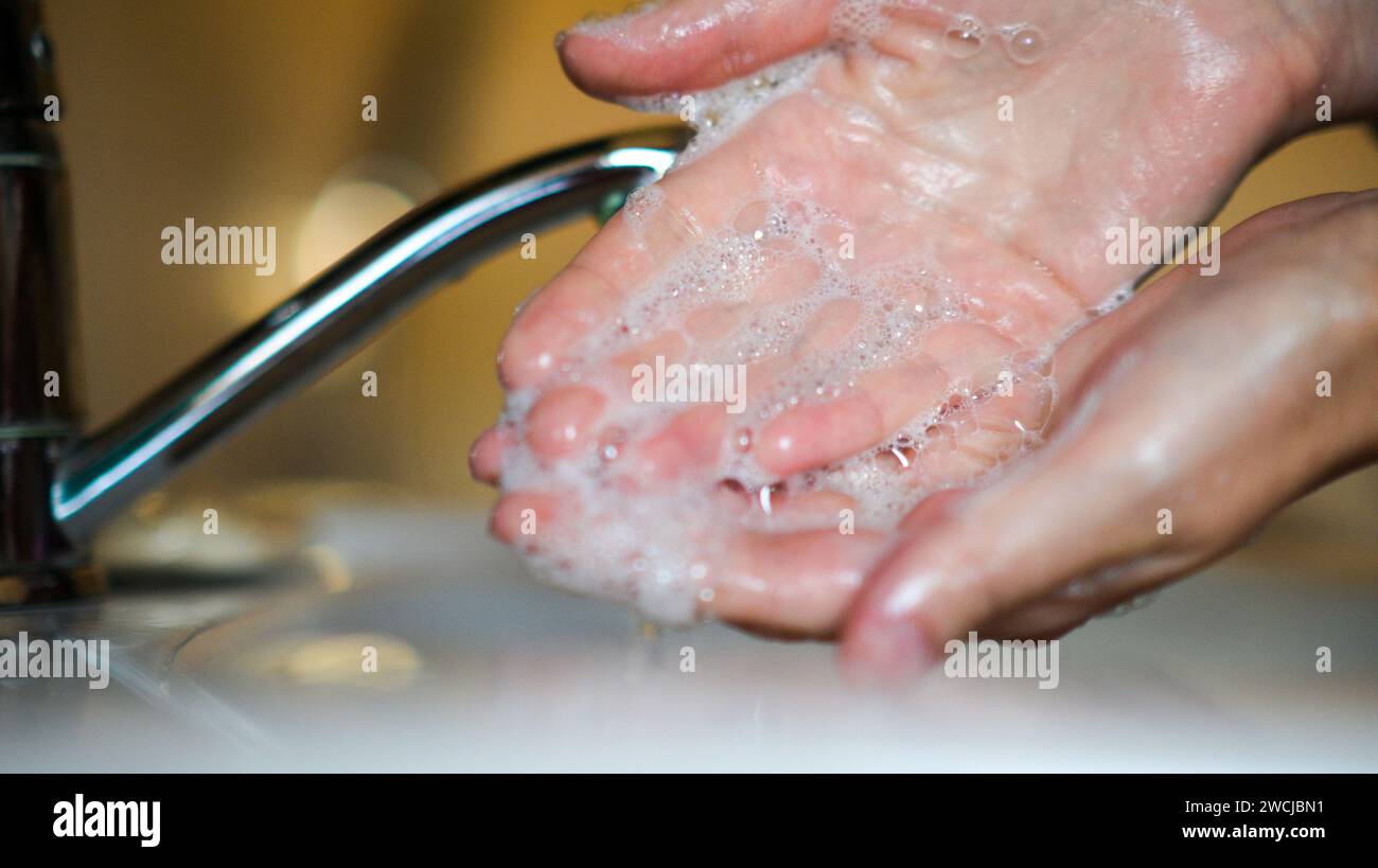 Die Frau wäscht sich die Hände unter fließendem Wasser, benutzt Seife. Stockfoto