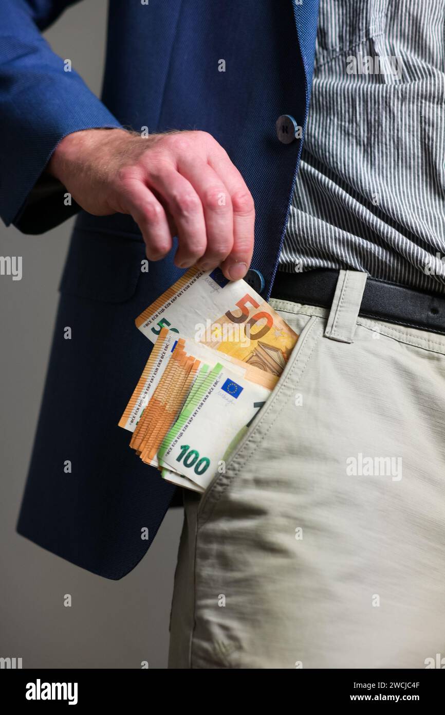 Ein Typ in einem blauen Anzug und einer leichten Hose zieht Geld aus seiner Tasche, aus der Nähe. Stockfoto